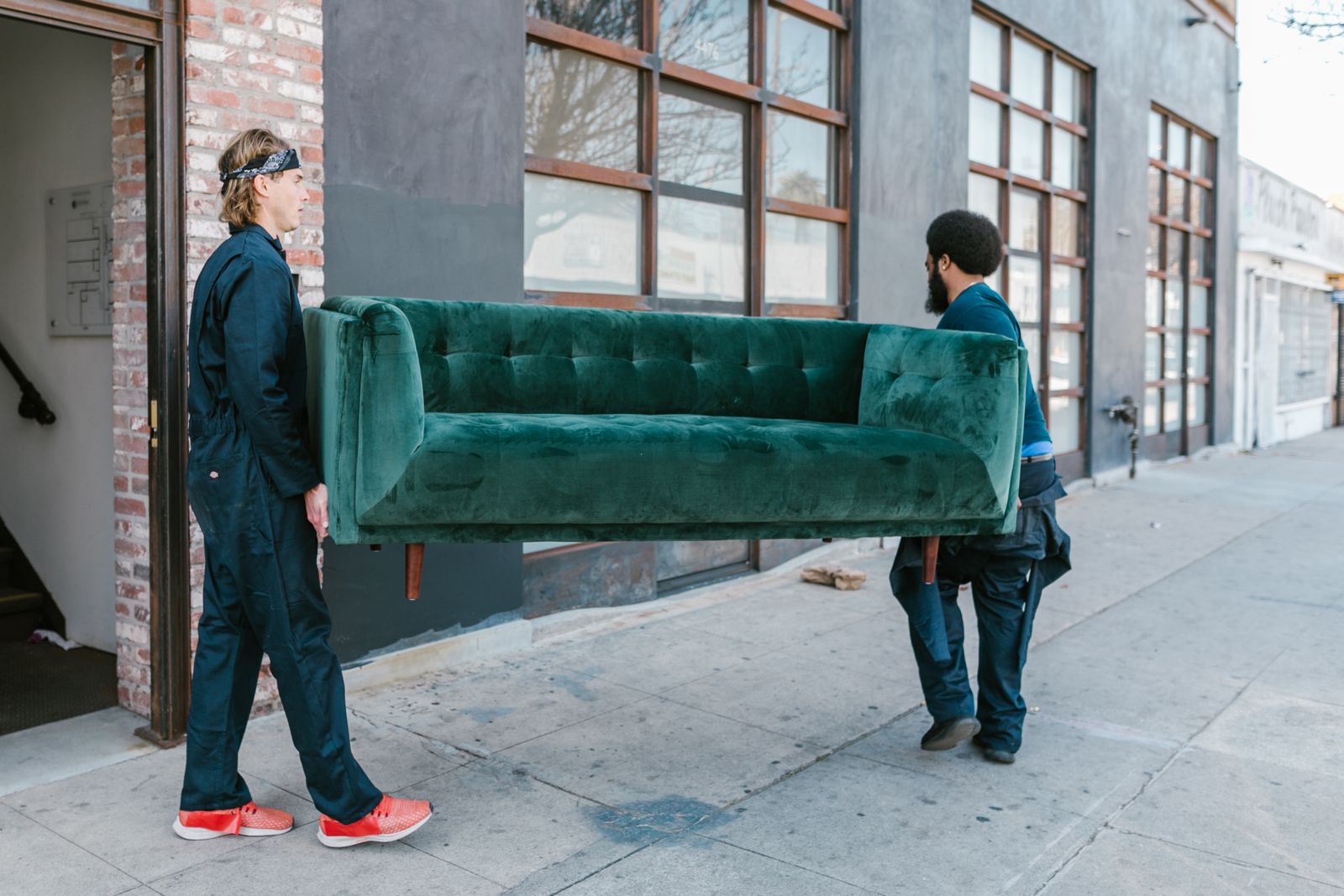 Two movers carrying a couch out to the truck